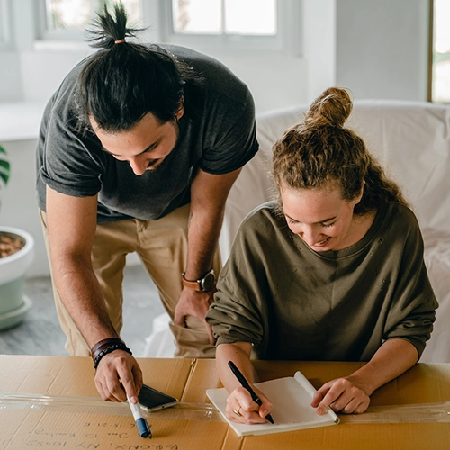 Photo of Couple Planning and Writing on Moving Boxes