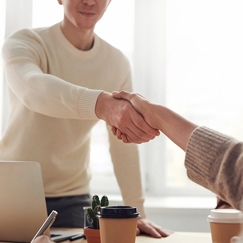 Man Shaking Hands over Desk